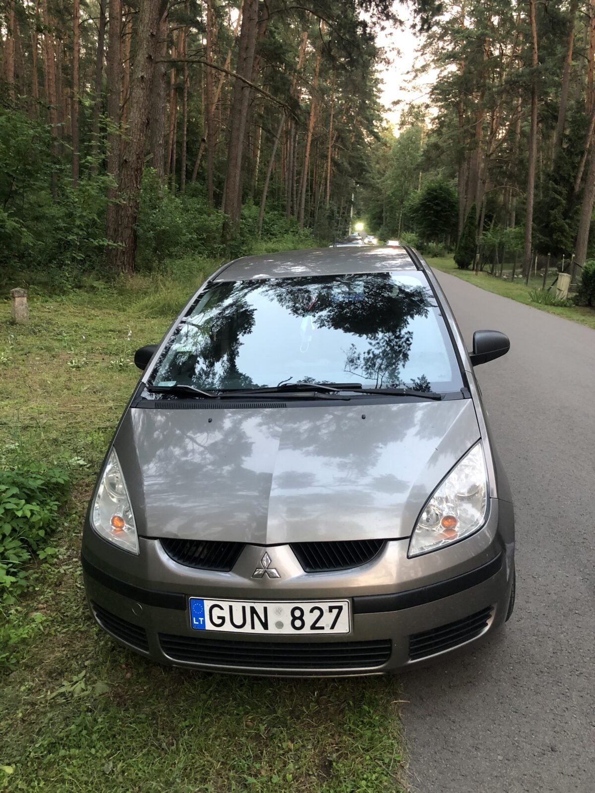 Automobilių supirkimas Pakruojyje: pilkas Mitsubishi Colt automobilis stovintis prie miško Pakruojo rajone.