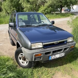 Tamsiai mėlynas Ford Maverick visureigis, pastatytas ant žolės šalia žvyrkelio, iliustruoja automobilių supirkimo paslaugas Klaipėdoje, kurias teikia AutoDylas.